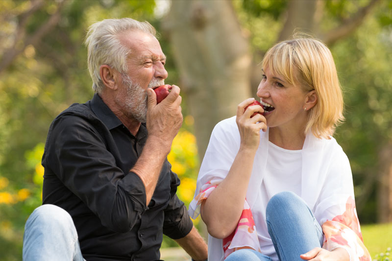 Older couple eating apples outdoors at a park